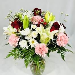 Bouquet of lilies, roses, carnations, and daisies in a glass vase