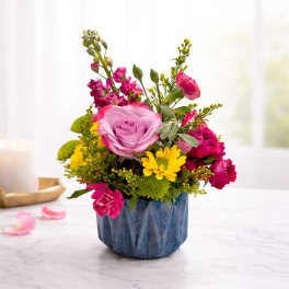 Pink and yellow flower arrangement in a blue ceramic pot