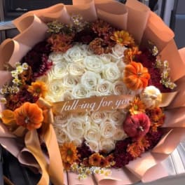 Bouquet of white roses with orange and burgundy flowers in peach wrapping