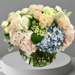 Pastel roses and hydrangeas arranged in a clear glass vase