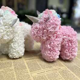 Two small unicorn figurines covered in pink and white roses