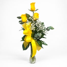 Yellow roses in a clear glass vase with baby's breath and a yellow ribbon
