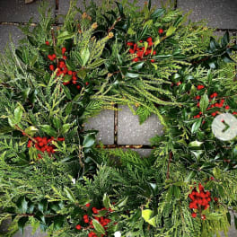 Evergreen wreath with glossy foliage and clusters of red berries on a stone surface
