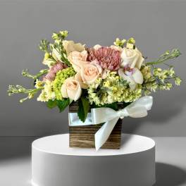 Bouquet of peach and cream roses with pink blooms in a wooden box