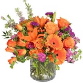 Orange and purple mixed bouquet in a glass vase