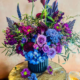 Purple and blue floral arrangement in a dark vase
