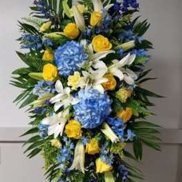 Tall blue, yellow, and white funeral spray on a stand