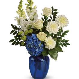 White and blue floral arrangement in a cobalt glass vase