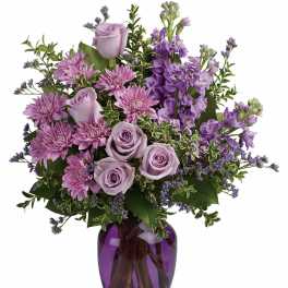 Lavender roses and purple flowers in a purple glass vase