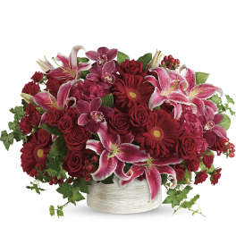 Red and pink floral arrangement in a white round container