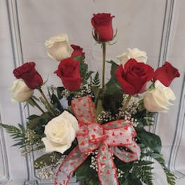 Red and white roses in a glass vase with a heart ribbon