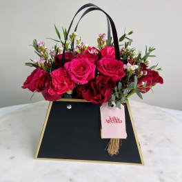 Pink and red roses in a black gift bag with handles