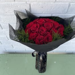 Bouquet of red roses wrapped in black paper with a ribbon
