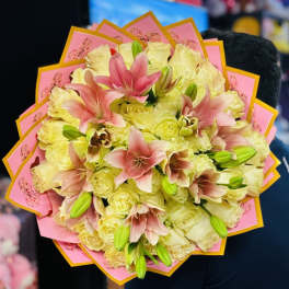 Bouquet of pale yellow roses and pink lilies wrapped in pink paper