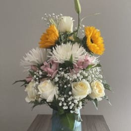 Mixed bouquet in a blue glass vase with white, pink, and yellow flowers