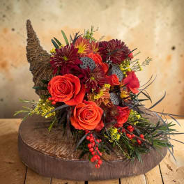 Orange roses and burgundy mums arranged in a rustic basket.