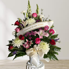 Standing sympathy spray with pink and white flowers and a memorial ribbon