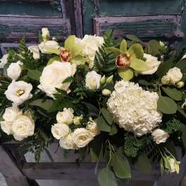 White floral arrangement with roses, hydrangea, and green orchids