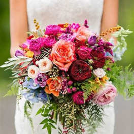 Bride holding a large colorful bouquet of roses and mixed flowers