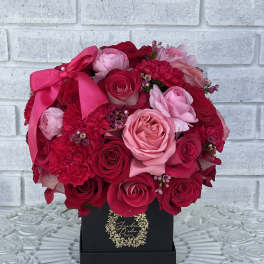 Pink and red rose bouquet in a black box with a satin bow