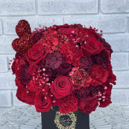 Red rose arrangement in a black box with a glittery heart accent