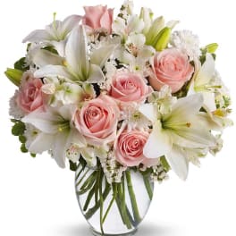 Pink roses and white lilies arranged in a clear glass vase