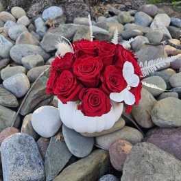 Red roses arranged in a white pumpkin-shaped vase with white butterfly accents