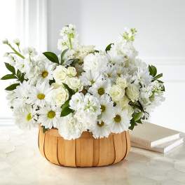 White daisies and roses arranged in a wooden basket