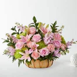 Pink roses and lilies arranged in a low wooden basket