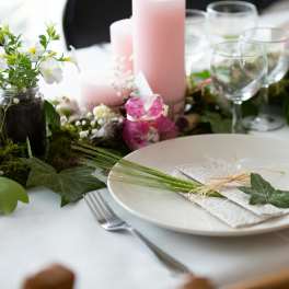 Floral table centerpiece with pink candles and white flowers on a set dining table