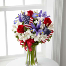 Bouquet of red roses and purple flowers with small American flags in a glass vase