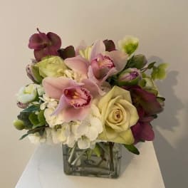 Bouquet of pink orchids and cream roses in a square glass vase