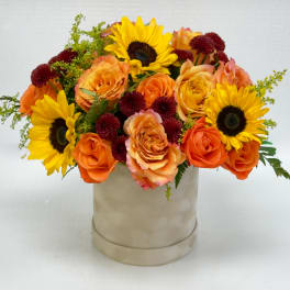 Orange roses and yellow sunflowers in a beige hatbox