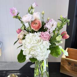 Mixed pink and white flowers arranged in a clear glass vase