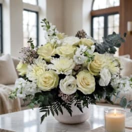 Cream roses and white blooms arranged in a ribbed vase on a table
