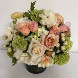 Bouquet of peach and white roses with green hydrangeas in a black vase