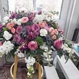 Large pink, white, and purple funeral spray on a stand
