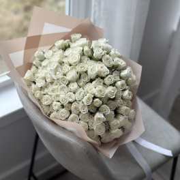 Large bouquet of white roses wrapped in pale pink paper