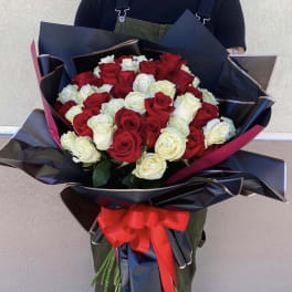 Large bouquet of red and white roses wrapped in black paper with a red ribbon