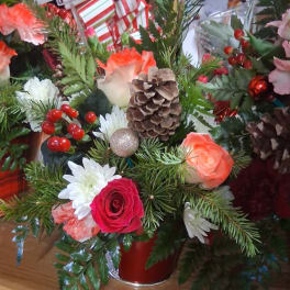 Holiday floral arrangement with roses, daisies, pinecones, and red berries in a red vase