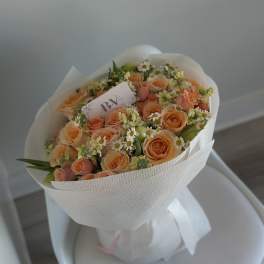 Peach rose bouquet with small white daisies wrapped in white paper