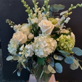 White roses and hydrangeas arranged in a glass vase with eucalyptus
