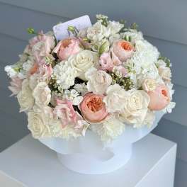 Round bouquet of white and blush roses in white wrapping
