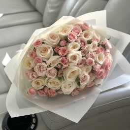 Bouquet of pink and cream roses wrapped in white paper