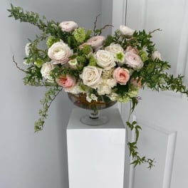 Pastel rose arrangement in a glass compote vase