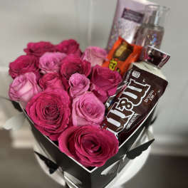 Pink and magenta roses in a black gift box with chocolates and perfume