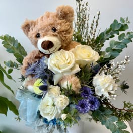 Teddy bear in a bouquet with white roses and purple flowers