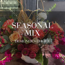 Mixed bouquet of coral, pink, white, and burgundy flowers in a white vase
