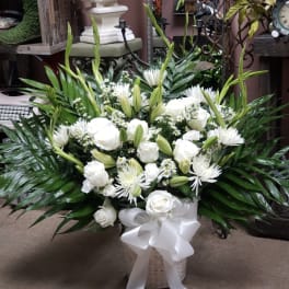 White roses and lilies in a basket with a white ribbon