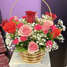 Basket arrangement of red and pink roses with white baby's breath